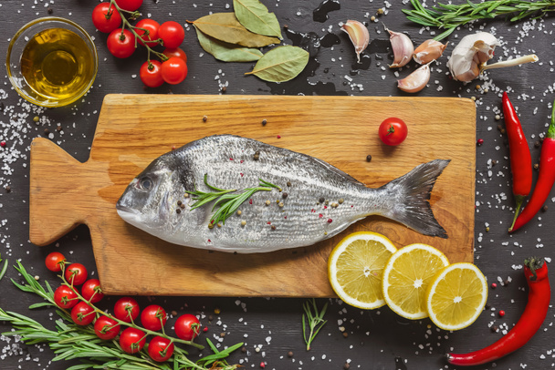 вид сверху на пищевой состав с сырой рыбой и ингредиентами на деревянной доске
 - Фото, изображение