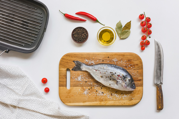 top view of cherry tomatoes, olive oil and uncooked fish on wooden board  - 写真・画像