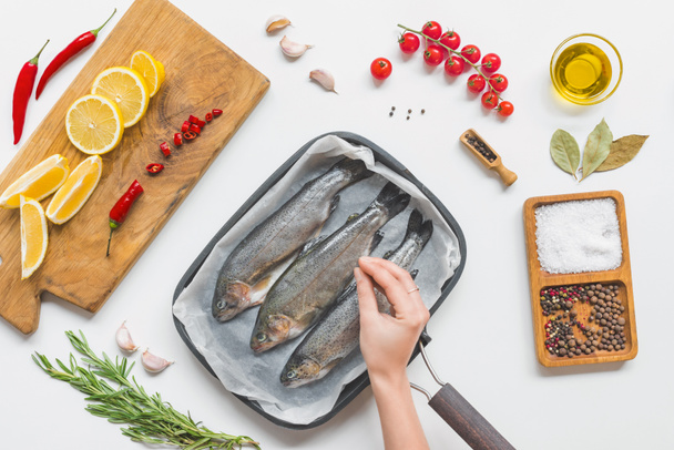 częściowy widok kobiety, oddanie, solenie surowe ryby w blasze na stole z składników  - Zdjęcie, obraz