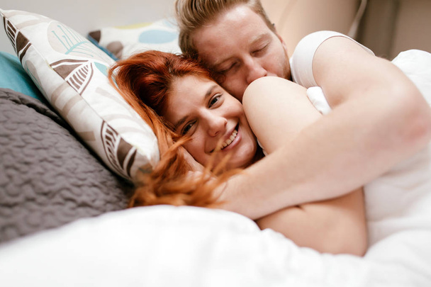 Beautiful couple in love awake  in bed and smiling - 写真・画像
