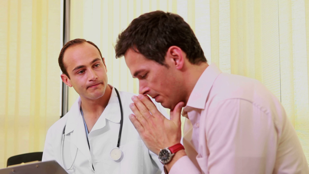 Doctor talking to a patient while they sit in a waiting room - Filmagem, Vídeo