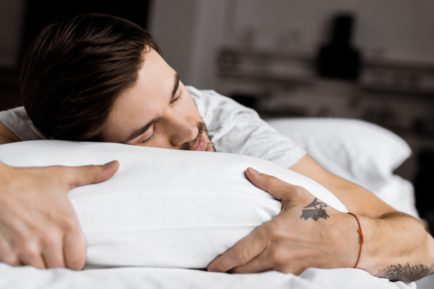 przystojny młody człowiek wytatuowany spanie na łóżku - Zdjęcie, obraz