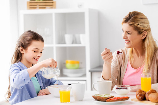 happy mother and daughter having breakfast at home - Zdjęcie, obraz