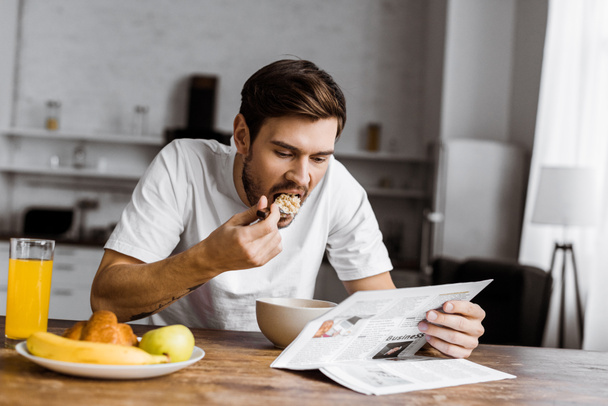 jeune homme ayant des céréales pour le petit déjeuner et la lecture de journal à la maison
 - Photo, image