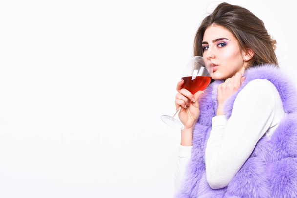 Lady curly hairstyle like expensive wine. Luxury life concept. Reasons drink red wine in wintertime. Alcohol and cold weather. Woman enjoy wine. Girl fashion makeup wear fur coat hold wine glass - Foto, imagen