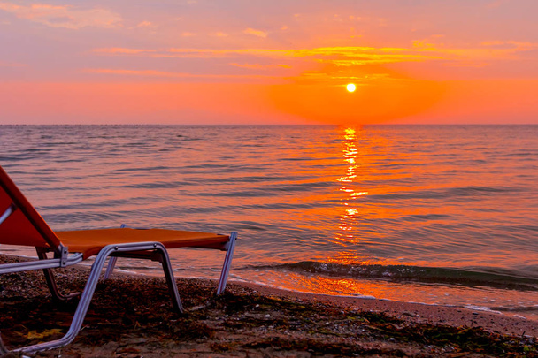 Вид рано утром Солнце, рассвет, на общественный пляж с соломенными зонтиками, зонтиками и шезлонгами вдоль береговой линии моря
. - Фото, изображение