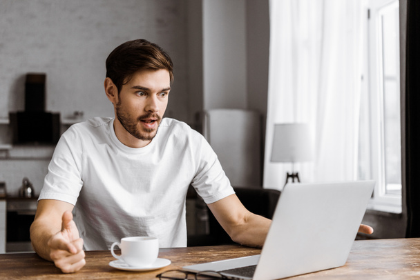 shocked young man with coffee using laptop at home - Photo, Image