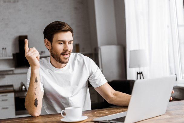 взволнованный молодой человек с кофе, используя ноутбук и глядя вверх по дому
 - Фото, изображение