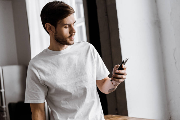 handsome young man using smartphone at home - Foto, Bild