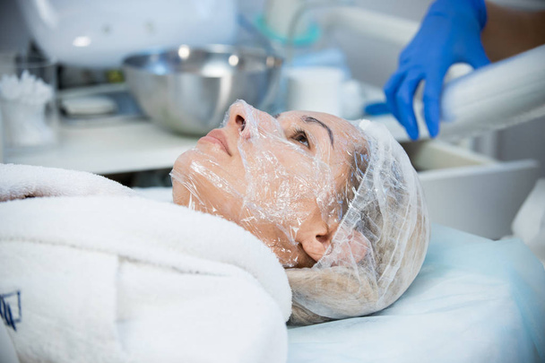 Clínica de Cosmetología. Procedimiento anti-envejecimiento. Poner polietileno en la cara
. - Foto, imagen