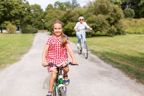 grandmother and granddaughter cycling at park - 写真・画像
