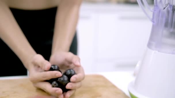 Slow motion - Sporty Asian woman using blender to make grape juice in the kitchen, beautiful female in sport clothing use organic fruit lots of nutrition herself at home. Healthy food concept. - Filmati, video