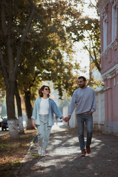 Couple walking on sidewalk holding hands on sunny day - Fotó, kép
