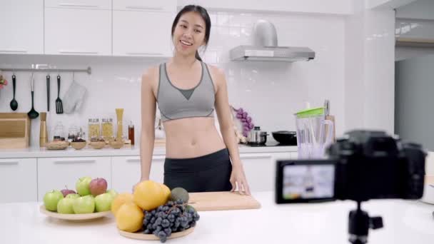 Blogger sporty Asian woman using camera recording how to make orange juice video for her subscriber, female use organic fruit making orange juice by herself at home. Healthy food concept. - Footage, Video