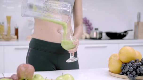 Σπορ ασιατική γυναίκα πίνοντας χυμό μήλου στην κουζίνα, όμορφη γυναίκα σε αθλητικά ρούχα Χρησιμοποιήστε πολλά βιολογικά φρούτα διατροφή παραγωγή χυμού Μήλου από τον εαυτό της στο σπίτι. Έννοια της υγιεινής διατροφής. - Πλάνα, βίντεο