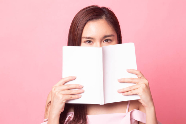 Young Asian woman got headache read a book on pink background - Фото, зображення