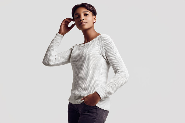 Portret van jonge mooie hipster zwarte meisje met kort haar lachend in witte trui geïsoleerd op een witte achtergrond. Studio shoot. - Foto, afbeelding