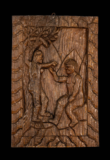 Наивная или народная резьба по дереву барельефная табличка, представляющая классическую тему Адама и Евы. Изолированный на черном
. - Фото, изображение