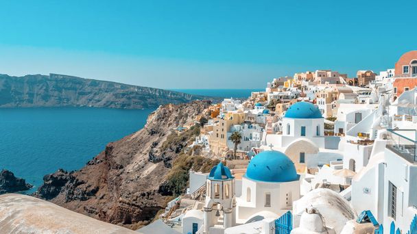 Widok miasta Oia z tradycyjnych i znanych domów i kościołów z niebieski kopuły na kalderę na wyspie Santorini. Grecja. - Zdjęcie, obraz