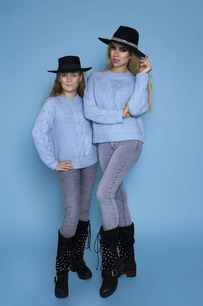 schöne blonde Mädchen, Mutter mit Tochter in herbstlicher Winterkleidung auf blauem Hintergrund im Atelier. - Foto, Bild