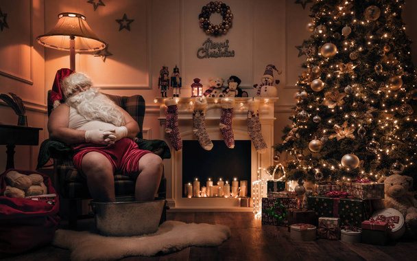 Santa Claus ontspannen na of voor werk in gezellige kerst kamer  - Foto, afbeelding