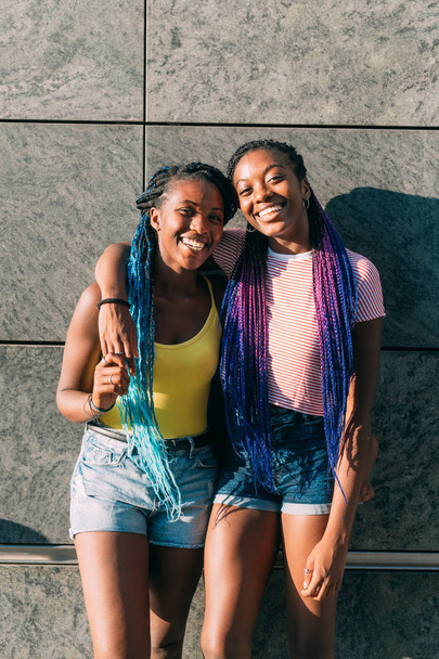 İki kız kardeş dışarıda poz veriyor kameraya sarılıyor gülümsüyor - mutluluk, bağ, bakım konsepti - Fotoğraf, Görsel