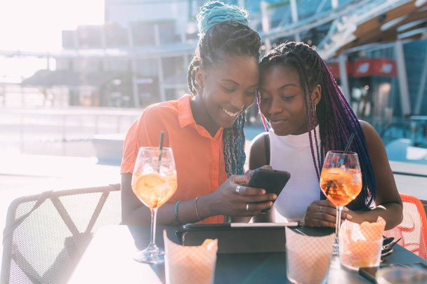 dvě ženy sestry sedí venku bar s happy hour pomocí chytrého telefonu - vstřícnost, technologie, relaxační koncept - Fotografie, Obrázek
