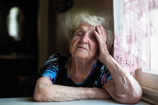 Віддана літня жінка на кухні свого будинку, сидячи за столом
. - Фото, зображення