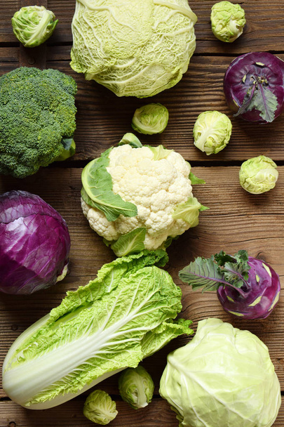 Different varieties of cabbages on wooden background. Organic fresh vegetables - cauliflower, kohlrabi, broccoli, purple cabbage. Raw food. Healthy food. - Photo, Image