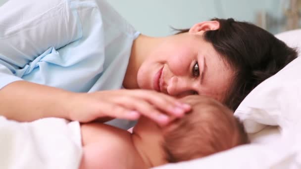 Mother looking at her sleeping baby head to head in a bed - Metraje, vídeo