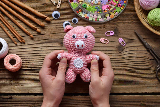 Pink Pig. Crochet toy for child. On table threads, needles, hook, cotton yarn. Handmade crafts, DIY concept. Small business. Income from hobby - Photo, Image