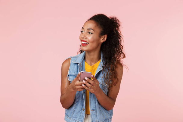 Image of pretty young happy beautiful woman posing isolated over pink background chatting by phone. - Foto, imagen