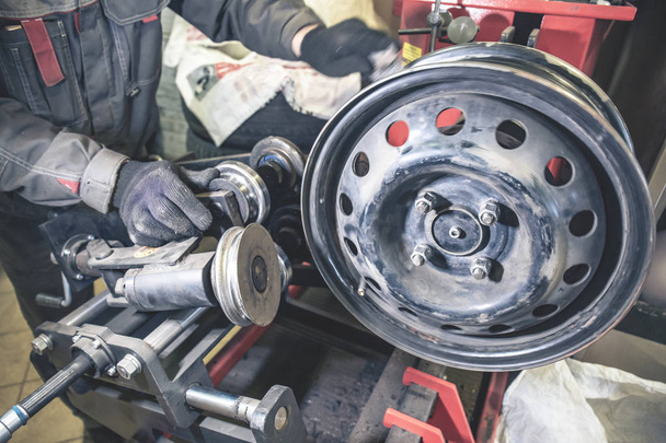 Repair and restoration of car wheel drive by mechanic master on professional machine equipment tool in car repair garage service, toned - Photo, Image