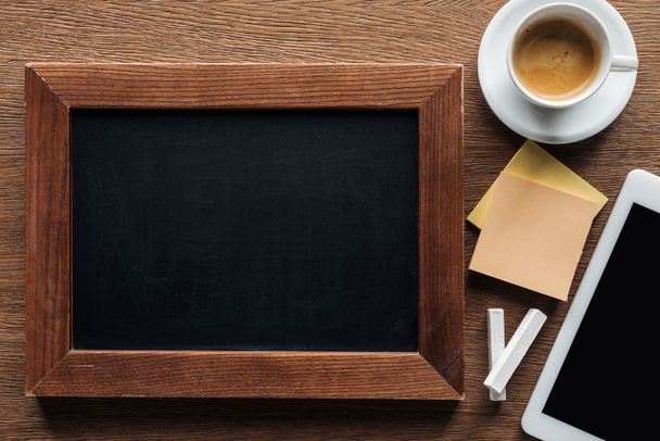 top view of blank chalk board with digital tablet and coffee on wooden background - Foto, immagini