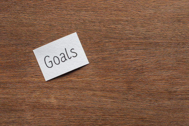 top view of 'goals' lettering on card with wooden background and copy space - Foto, Imagem