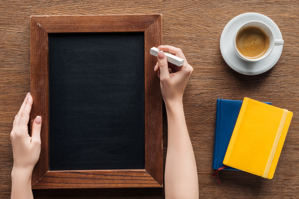 cropped view of woman writing with chalk on blank wooden board - Photo, Image