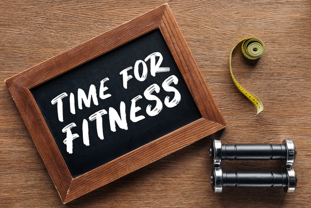 fita métrica, halteres e placa de giz de madeira com 'tempo para fitness' citação, dieta e conceito de estilo de vida saudável
 - Foto, Imagem