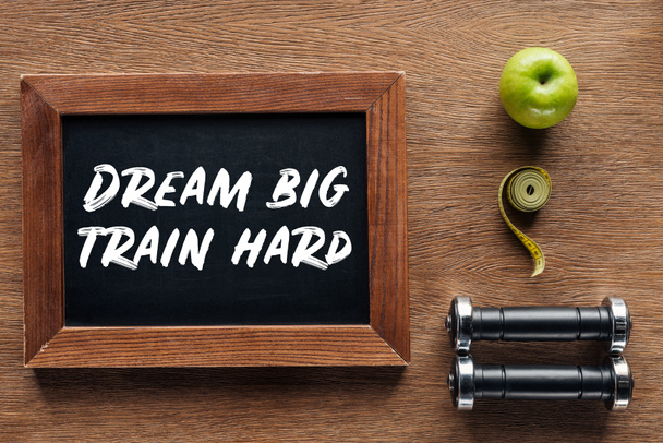 apple, dumbbells, measuring tape and wooden chalk board with 'dream big train hard' quote, dieting and healthy lifesyle concept - Photo, Image