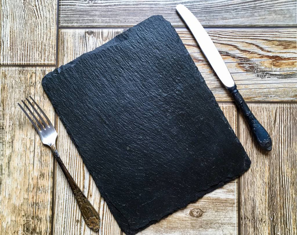 Placa de piedra negra con cuchillo y tenedor
 - Foto, Imagen