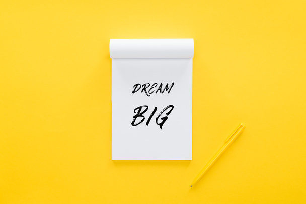 Draufsicht auf Notizbuch mit 'dream big' Zitat auf gelb, Zielsetzungskonzept - Foto, Bild