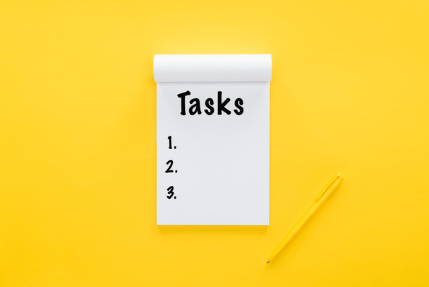 Notizbuch von oben mit Aufgabenliste auf gelb - Foto, Bild