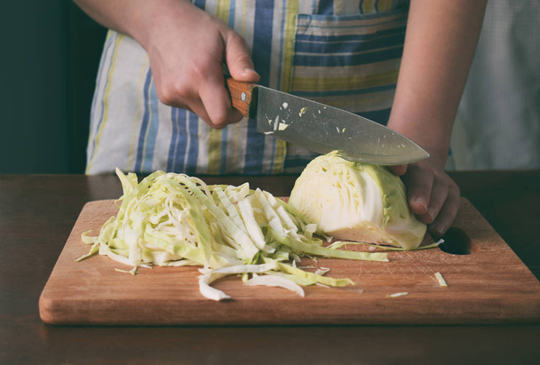 Жінка готує квашену капусту або салат на дерев'яному тлі. Крок 1 - подрібніть капусту. Ферментовані консервовані овочі концепція харчування
 - Фото, зображення