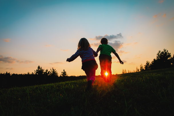 Silhouet van gelukkige jongen en meisje met spelen bij zonsondergang - Foto, afbeelding