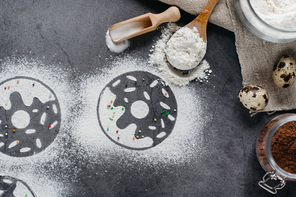 Ingredients for donuts baking. Spoon with flour, dishes, eggs, sugar  on a grey background.Bakery background frame. Top view, copy space. - Фото, зображення