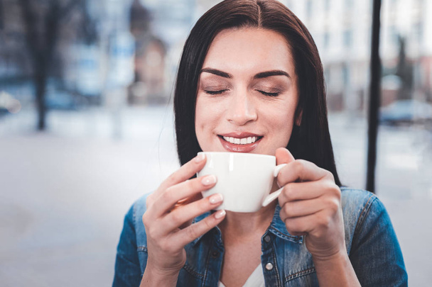 Portrait of delighted girl that smelling good coffee - Fotó, kép