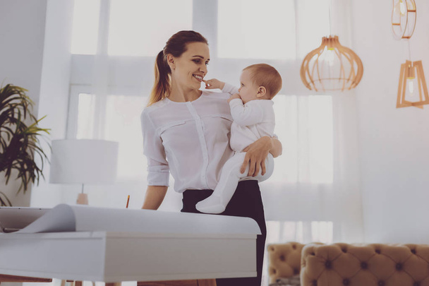 Little cute baby touching her industrious working parent in lighted room - Фото, зображення