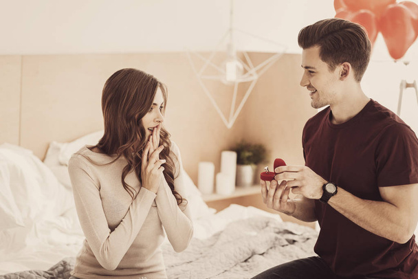 Charming girlfriend feeling shocked while receiving unbelievable engagement ring - 写真・画像