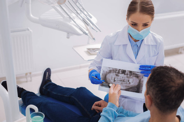 Professional dentist showing an X ray image to her patient - Fotoğraf, Görsel