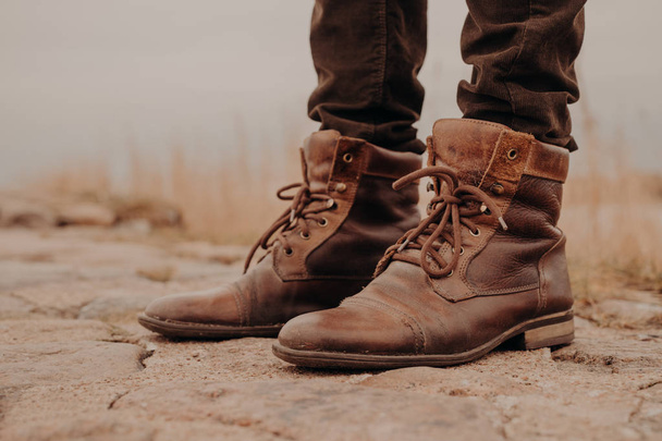 Imagem de pernas de homem em botas velhas. Conceito de vender sapatos. Hora do Outono. Vista horizontal. Tiro ao ar livre. Calçado
 - Foto, Imagem
