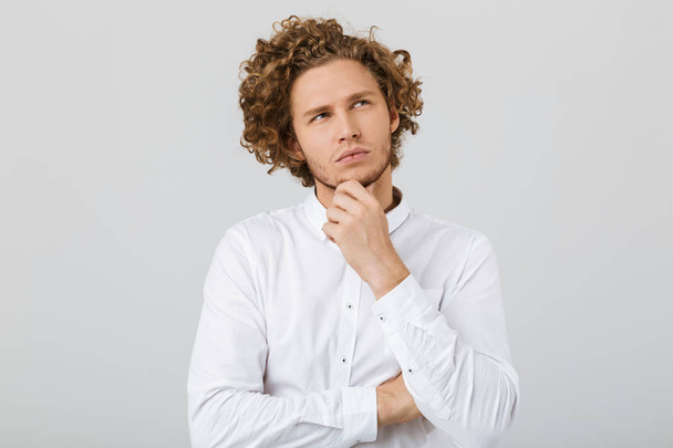 Portrait of a pensive young man with curly hair isolated over white background, looking away - Fotoğraf, Görsel